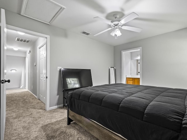 bedroom with ceiling fan, light colored carpet, and ensuite bath