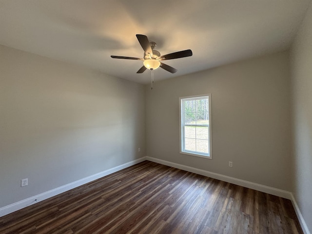 empty room with dark wood-style flooring, a ceiling fan, and baseboards