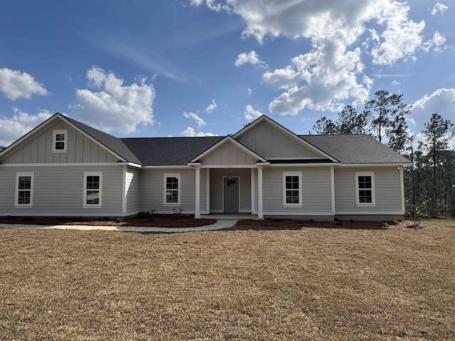 view of front of house with roof with shingles, board and batten siding, and a front yard