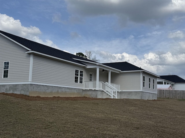 view of front of home with ceiling fan, a front yard, and fence