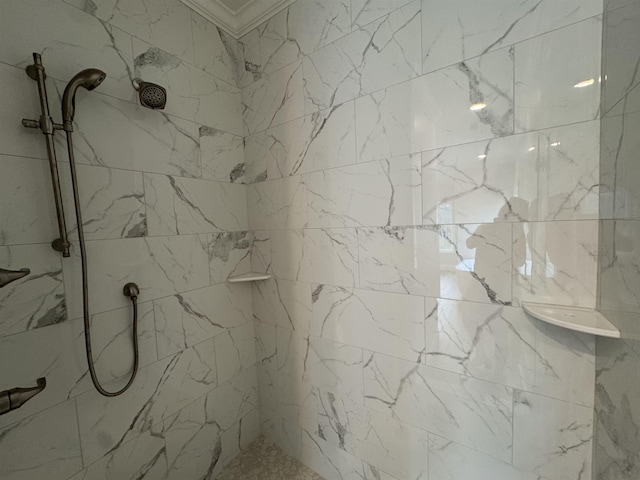 bathroom featuring a tile shower and crown molding