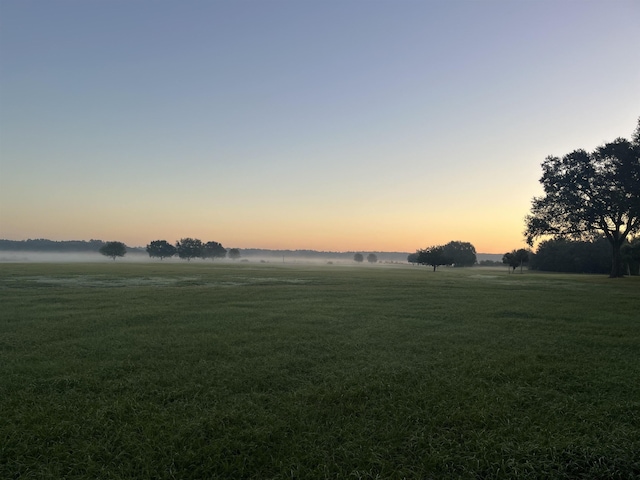 yard at dusk featuring a rural view