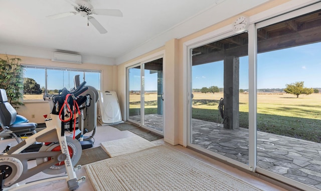 sunroom featuring plenty of natural light, a wall mounted AC, and ceiling fan