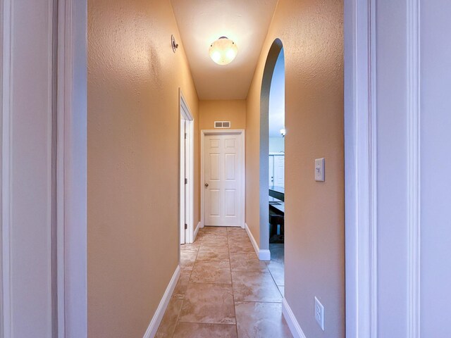14135 98th St, Live Oak, FL 32060 - hall with arched walkways, baseboards, a textured wall, and light tile patterned flooring