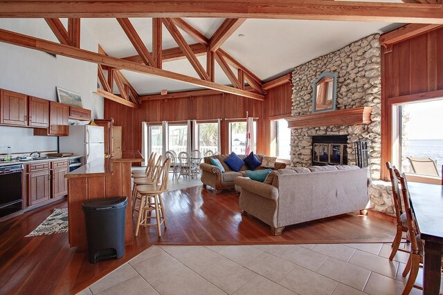 2289 Surf Rd Unit 12, Panacea, FL 32346 - living area featuring light tile patterned floors, wooden walls, beamed ceiling, a fireplace, and high vaulted ceiling