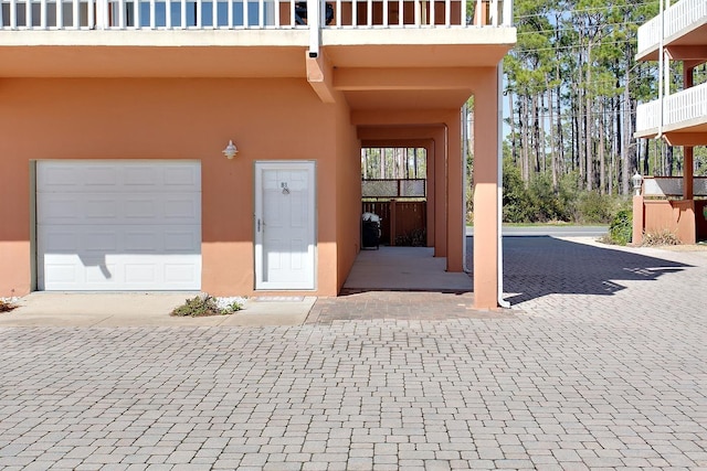 2289 Surf Rd Unit 12, Panacea, FL 32346 - view of exterior entry featuring a balcony, a garage, decorative driveway, and stucco siding