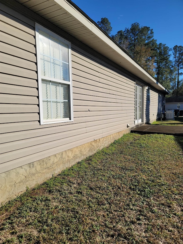 view of side of property featuring a yard and central AC