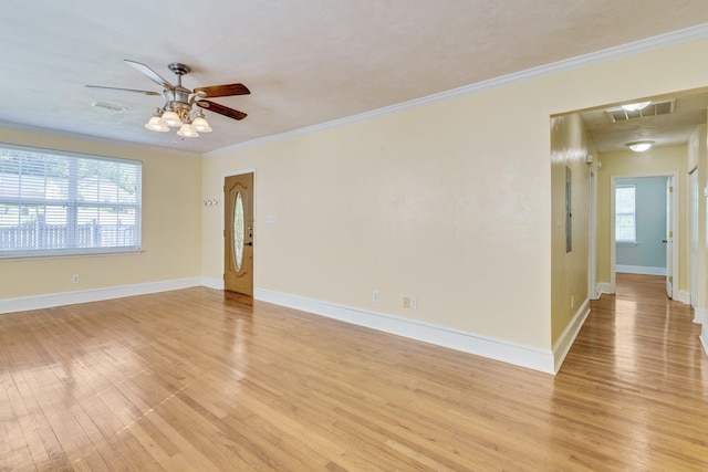 empty room featuring crown molding, ceiling fan, a healthy amount of sunlight, and light wood-type flooring