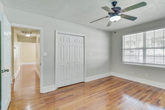 unfurnished bedroom featuring ceiling fan, light wood-type flooring, and a closet