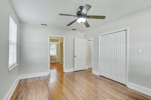 unfurnished bedroom with ceiling fan, wood-type flooring, and multiple windows