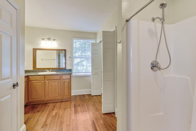 bathroom with hardwood / wood-style floors, vanity, and walk in shower