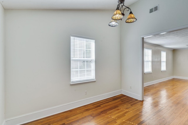 unfurnished room with ceiling fan with notable chandelier and wood-type flooring