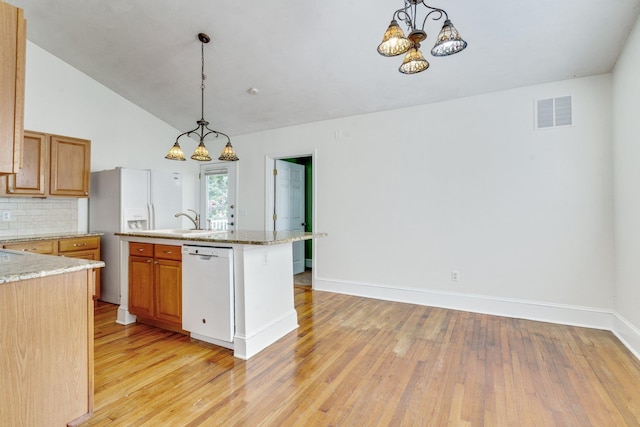 kitchen with tasteful backsplash, white appliances, a center island with sink, a notable chandelier, and hanging light fixtures