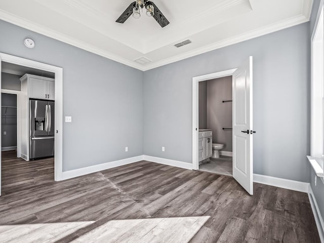 unfurnished bedroom with ornamental molding, a tray ceiling, dark hardwood / wood-style floors, and stainless steel fridge with ice dispenser