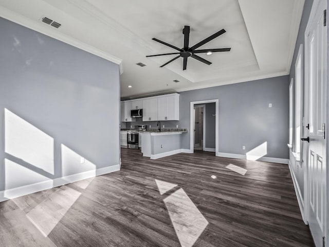 unfurnished living room with ceiling fan, ornamental molding, dark hardwood / wood-style flooring, and a raised ceiling