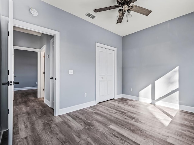 unfurnished bedroom with a closet, dark hardwood / wood-style floors, and ceiling fan