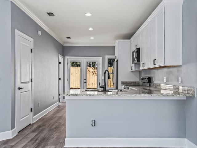 kitchen with stainless steel appliances, white cabinetry, french doors, and kitchen peninsula