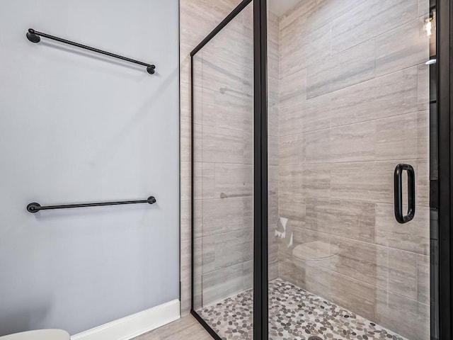 bathroom featuring a shower with door and toilet