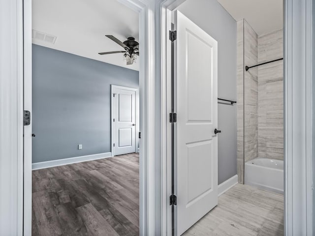 bathroom with tiled shower / bath combo, wood-type flooring, and ceiling fan