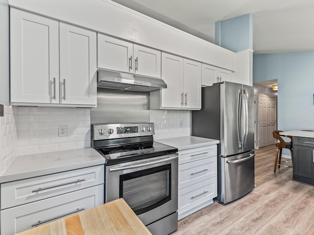 9 Pirates Cove Ln, Saint Marks, FL 32355 - kitchen featuring appliances with stainless steel finishes, under cabinet range hood, light wood-style floors, white cabinets, and decorative backsplash