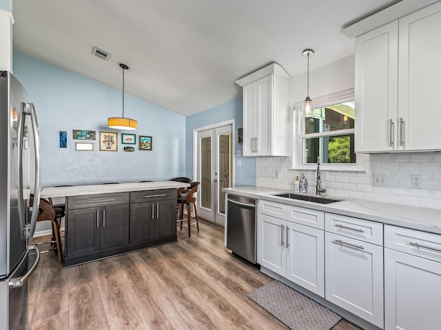 9 Pirates Cove Ln, Saint Marks, FL 32355 - kitchen with appliances with stainless steel finishes, lofted ceiling, white cabinetry, wood finished floors, and backsplash