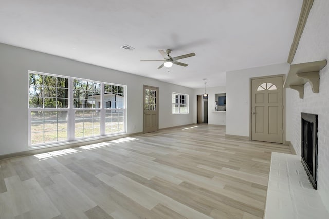 unfurnished living room with visible vents, a brick fireplace, baseboards, ceiling fan, and light wood-style flooring