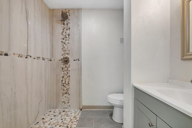 full bathroom with tile patterned floors, toilet, a tile shower, baseboards, and vanity