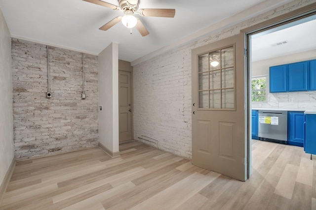 unfurnished room with visible vents, brick wall, light wood-type flooring, and a ceiling fan