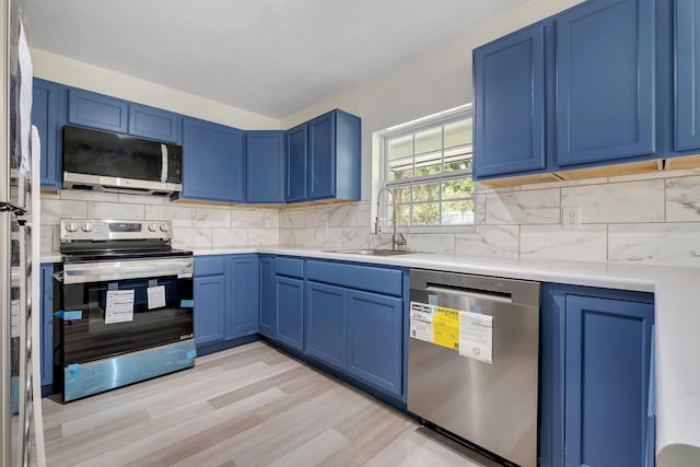 kitchen with blue cabinets, backsplash, and appliances with stainless steel finishes