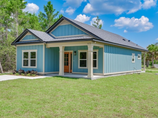 1673 Landing St, Carrabelle, FL 32322 - view of front of property with board and batten siding, roof with shingles, and a front lawn