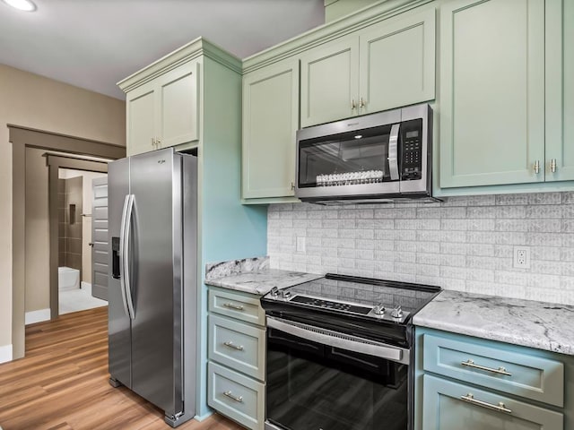 1673 Landing St, Carrabelle, FL 32322 - kitchen with appliances with stainless steel finishes, light wood-type flooring, backsplash, light stone countertops, and green cabinetry