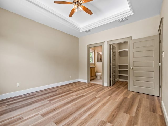1673 Landing St, Carrabelle, FL 32322 - unfurnished bedroom featuring light wood-style flooring, baseboards, a tray ceiling, and ensuite bathroom