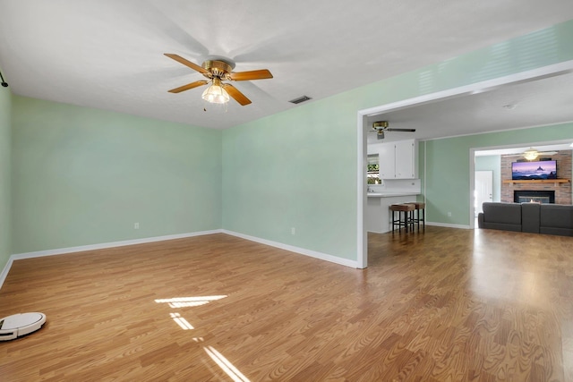 interior space with a fireplace, ceiling fan, and light wood-type flooring