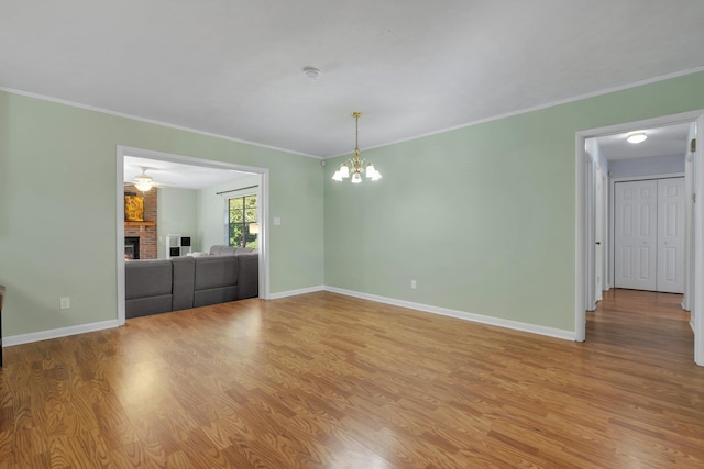 interior space with ornamental molding, a fireplace, a chandelier, and light hardwood / wood-style flooring