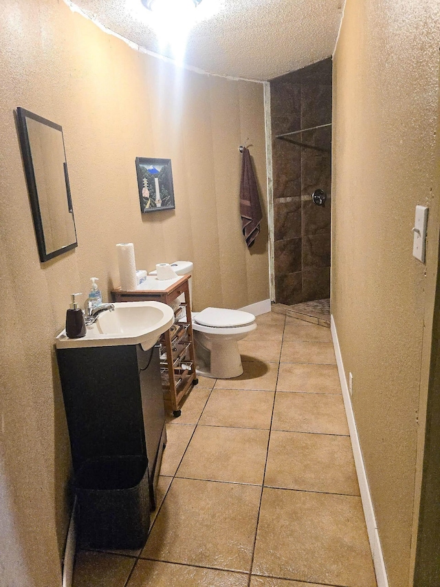 bathroom featuring vanity, tiled shower, toilet, tile patterned floors, and a textured ceiling