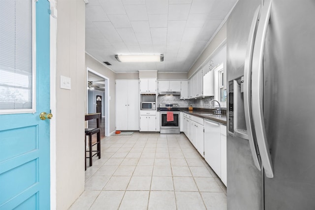 kitchen featuring sink, light tile patterned floors, stainless steel appliances, white cabinets, and decorative backsplash