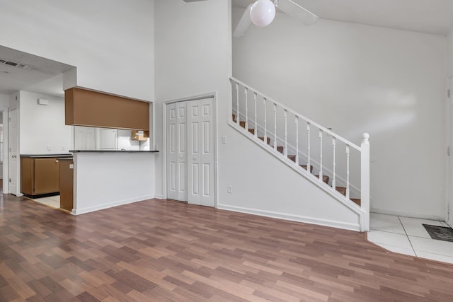 2467 Nugget Ln, Tallahassee, FL 32303 - unfurnished living room featuring wood finished floors, high vaulted ceiling, ceiling fan, baseboards, and stairway