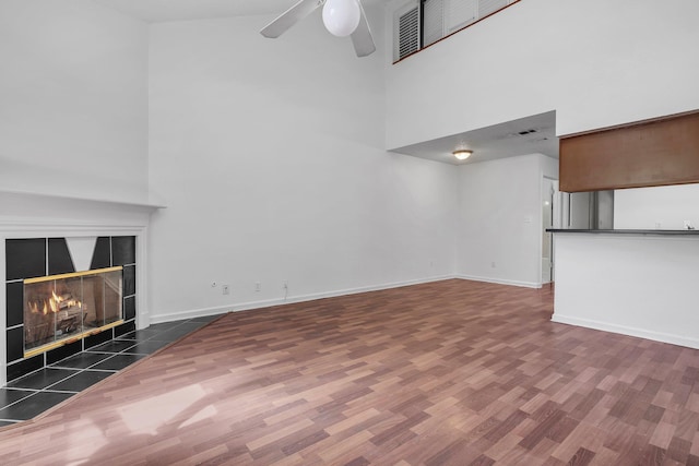 2467 Nugget Ln, Tallahassee, FL 32303 - unfurnished living room featuring a high ceiling, wood finished floors, a ceiling fan, a fireplace, and baseboards