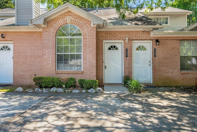 2467 Nugget Ln, Tallahassee, FL 32303 - property entrance with brick siding, roof with shingles, and a chimney