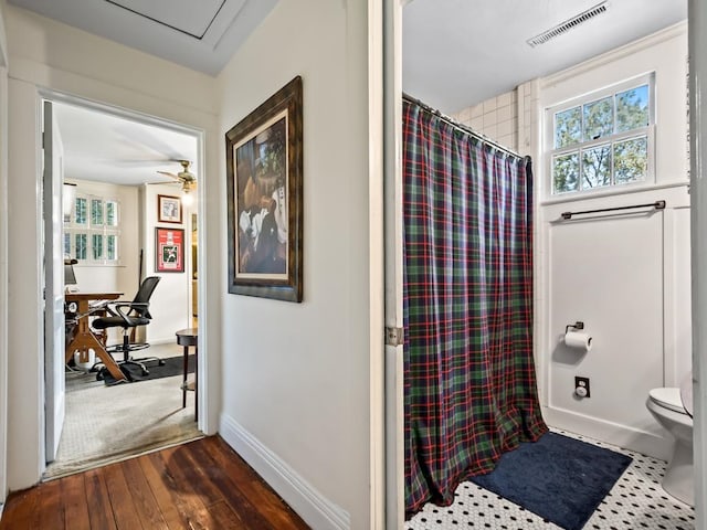 bathroom featuring toilet, curtained shower, hardwood / wood-style flooring, and ceiling fan