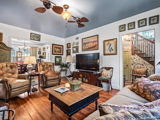 living room with wood-type flooring, crown molding, and ceiling fan with notable chandelier