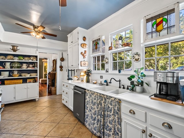 kitchen with light tile patterned flooring, sink, ornamental molding, stainless steel dishwasher, and white cabinets