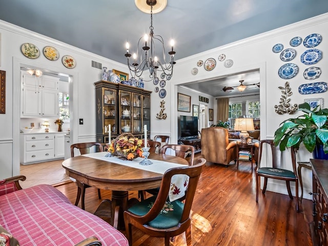 dining room featuring hardwood / wood-style floors, ceiling fan with notable chandelier, and crown molding