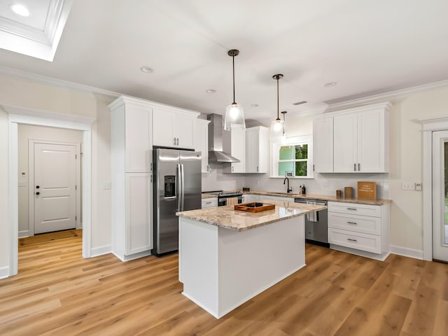 kitchen featuring white cabinets, appliances with stainless steel finishes, wall chimney exhaust hood, and hanging light fixtures