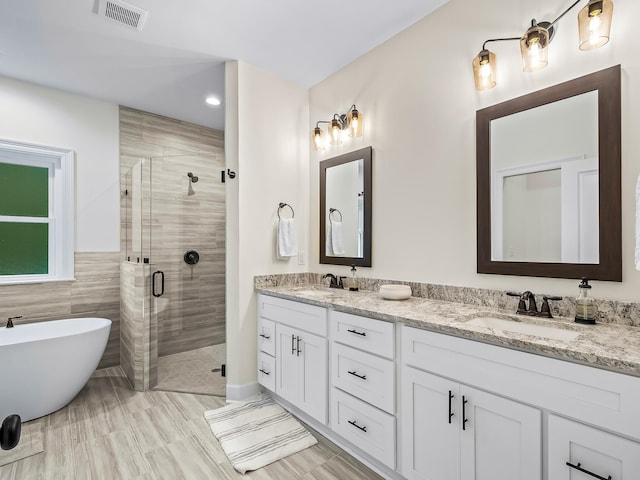 bathroom with tile walls, hardwood / wood-style floors, shower with separate bathtub, and vanity