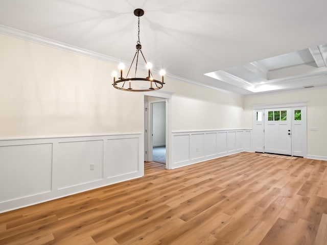 empty room featuring ornamental molding, light wood-type flooring, and a chandelier