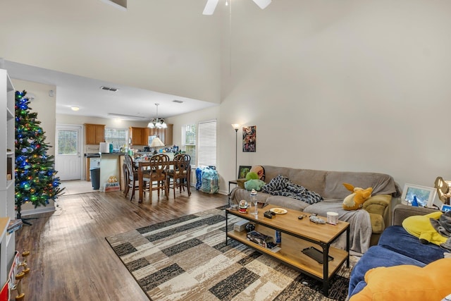 living room featuring ceiling fan with notable chandelier, hardwood / wood-style floors, and a towering ceiling