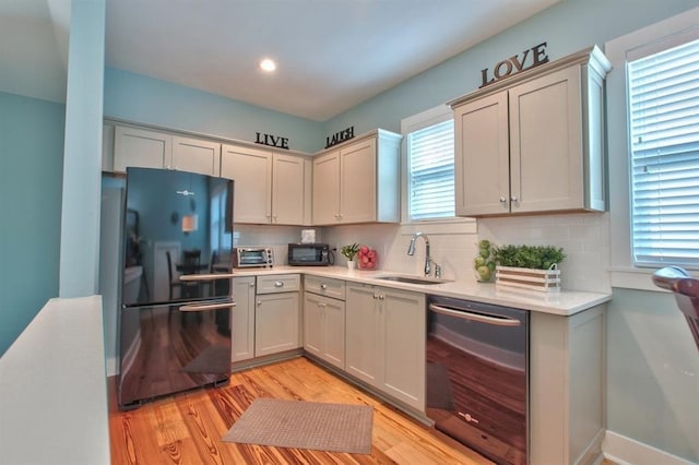 1261 Myrtle View Dr, Tallahassee, FL 32312 - kitchen featuring decorative backsplash, light wood-style floors, light countertops, a sink, and black appliances