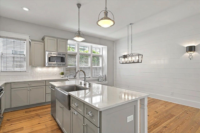 1261 Myrtle View Dr, Tallahassee, FL 32312 - kitchen featuring appliances with stainless steel finishes, a sink, an island with sink, gray cabinets, and light wood-type flooring