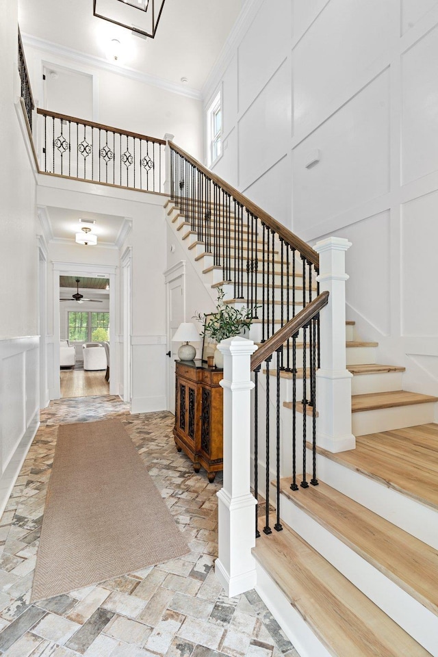 stairway with crown molding and a towering ceiling